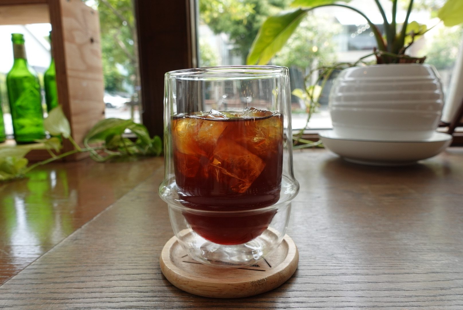 中庭の緑が見える窓辺のテーブルに置かれたアイスコーヒー